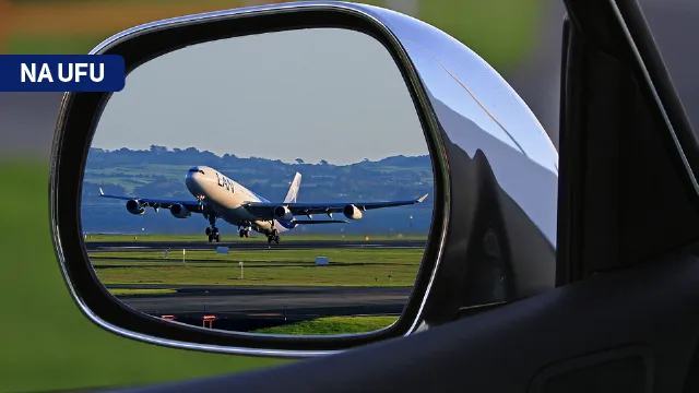 Foto de um avião visto pelo retrovisor de um carro